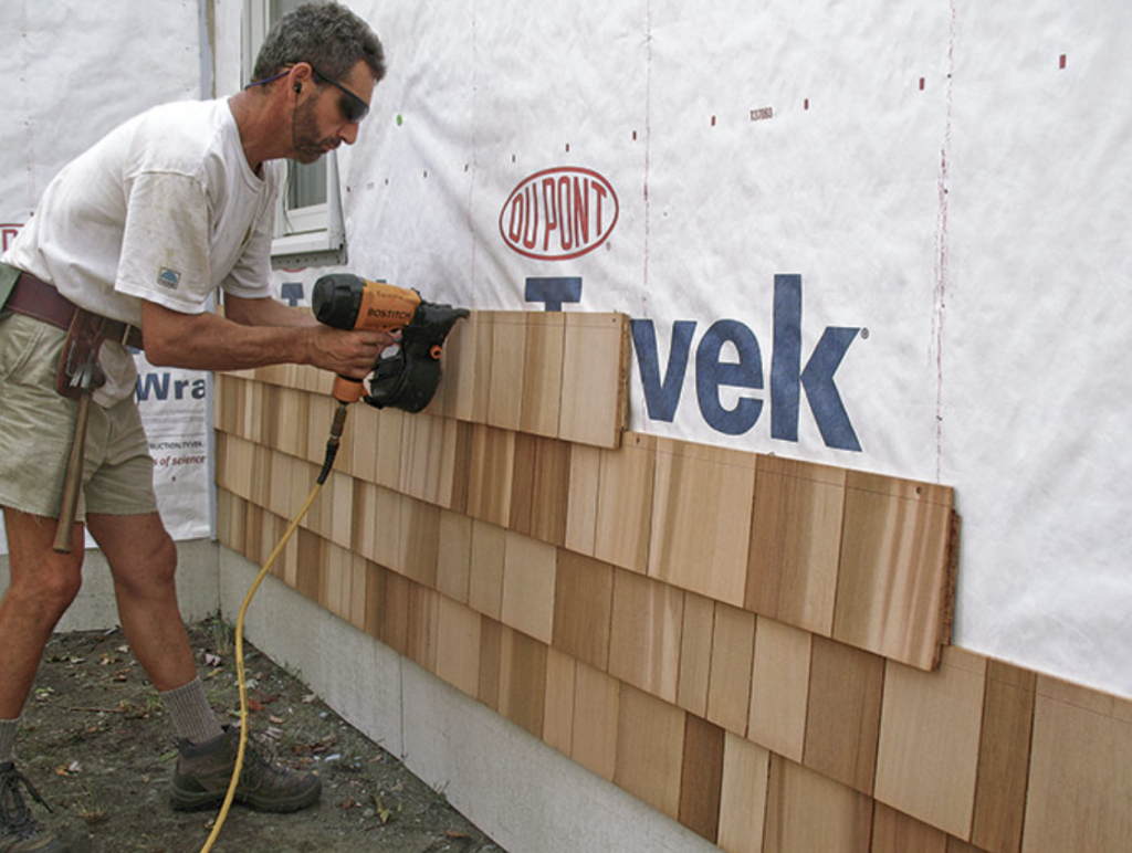 Siding contractor in Seattle installs cedar siding on house exterior wall